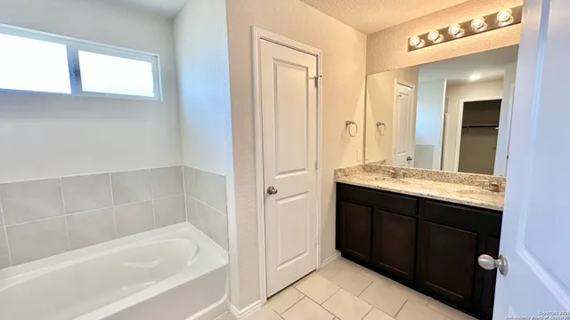 a bathroom with a granite countertop tub sink and mirror