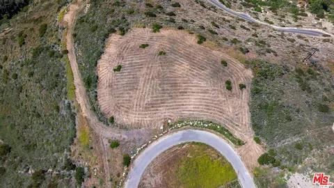 a aerial view of a house with a yard and trees all around