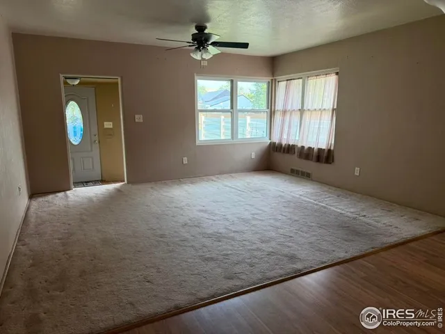 an empty room with windows and ceiling fan