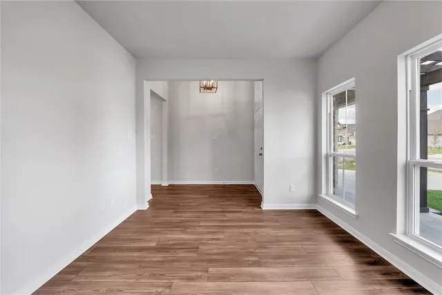a view of an empty room with wooden floor and window