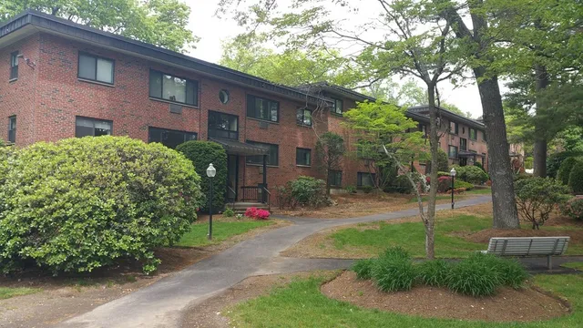 a view of a brick house with a yard and plants