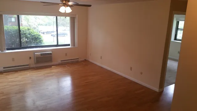 an empty room with wooden floor and windows