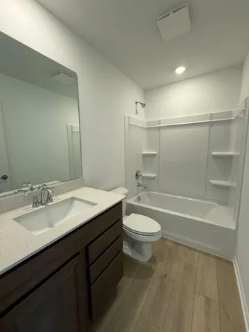 a bathroom with a bathtub shower sink vanity mirror and toilet