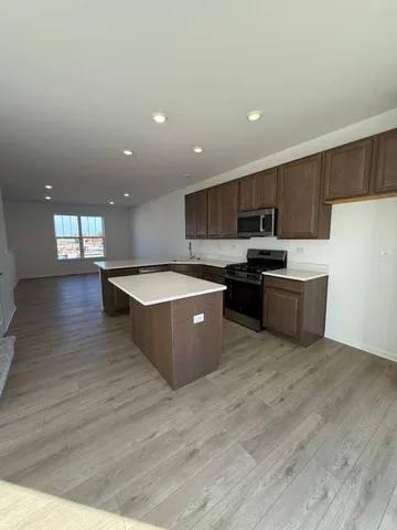 a large kitchen with stainless steel appliances granite countertop a large counter top a sink a refrigerator and a stove