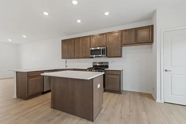 a kitchen with stainless steel appliances granite countertop a stove a sink and a refrigerator with wooden floor