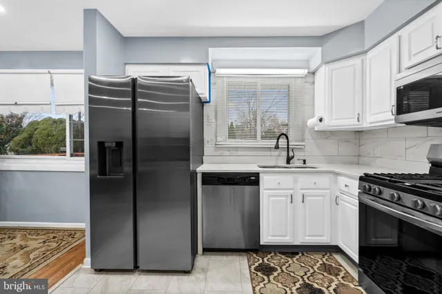 a kitchen with stainless steel appliances granite countertop a refrigerator a sink and a stove