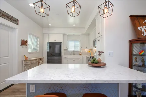 a kitchen with stainless steel appliances granite countertop a stove top oven a refrigerator a sink and dishwasher with wooden floor