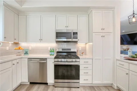 a kitchen with cabinets stainless steel appliances and wooden floor