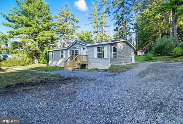 a view of a house with a yard and large trees