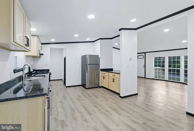 a kitchen with stainless steel appliances granite countertop a refrigerator a sink a stove and a wooden floors