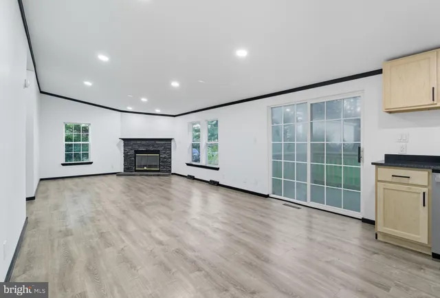 an empty room with wooden floor fireplace and windows