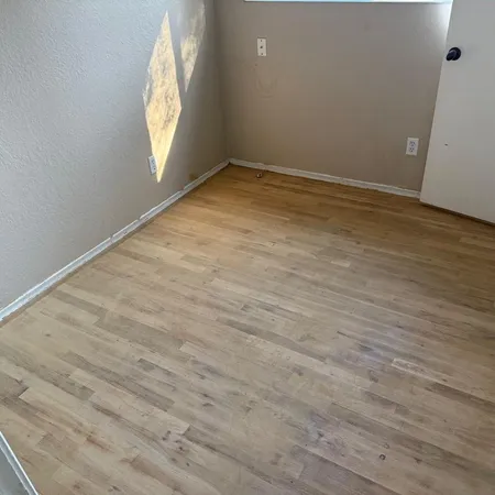 an empty room with window and wooden floor