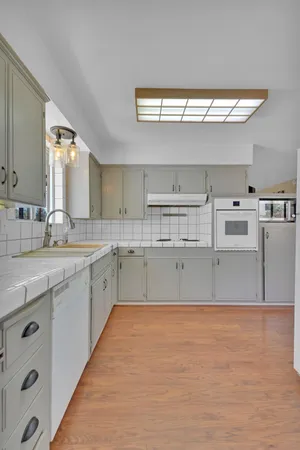 a large kitchen with stainless steel appliances a large white kitchen island a sink dishwasher and a stove