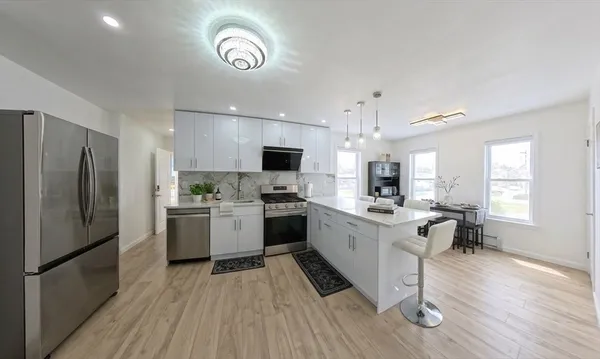 a kitchen with a refrigerator a sink dishwasher a oven with white cabinets and wooden floor