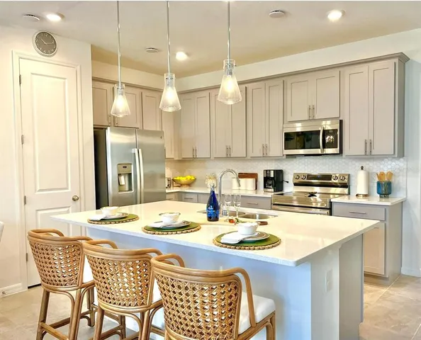 a kitchen with stainless steel appliances kitchen island granite countertop a stove a sink a refrigerator a dining table and chairs with wooden floor