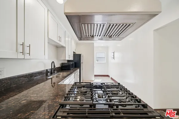 a kitchen with stainless steel appliances granite countertop white refrigerator stove and white cabinets