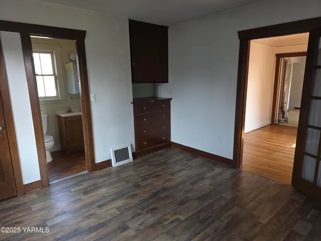 a view of a hallway with wooden floor and a cabinet