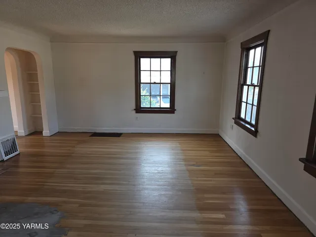 a view of an empty room with wooden floor and a window
