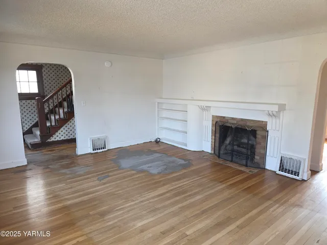 a view of empty room with wooden floor and fireplace