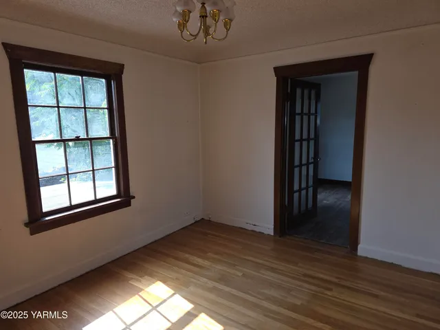 an empty room with wooden floor closet and windows