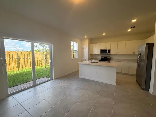 a large kitchen with a refrigerator a stove top oven a sink and a large window