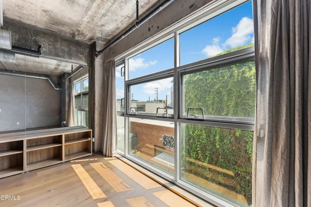 a view of an empty room with wooden floor and windows