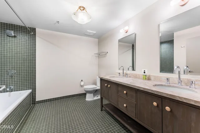 a spacious bathroom with a double vanity sink a mirror and a toilet