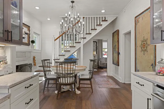 a kitchen with stainless steel appliances kitchen island granite countertop a stove a sink dishwasher and white cabinets with wooden floor