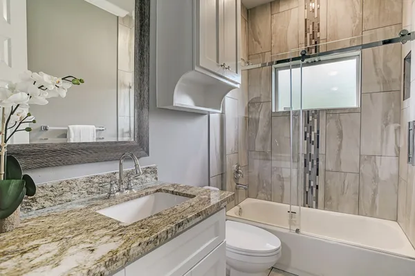 a bathroom with a granite countertop sink toilet and shower