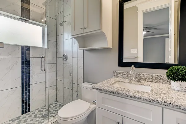 a bathroom with a granite countertop sink toilet and shower