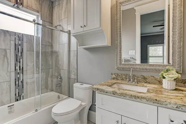 a bathroom with a granite countertop sink a toilet and shower
