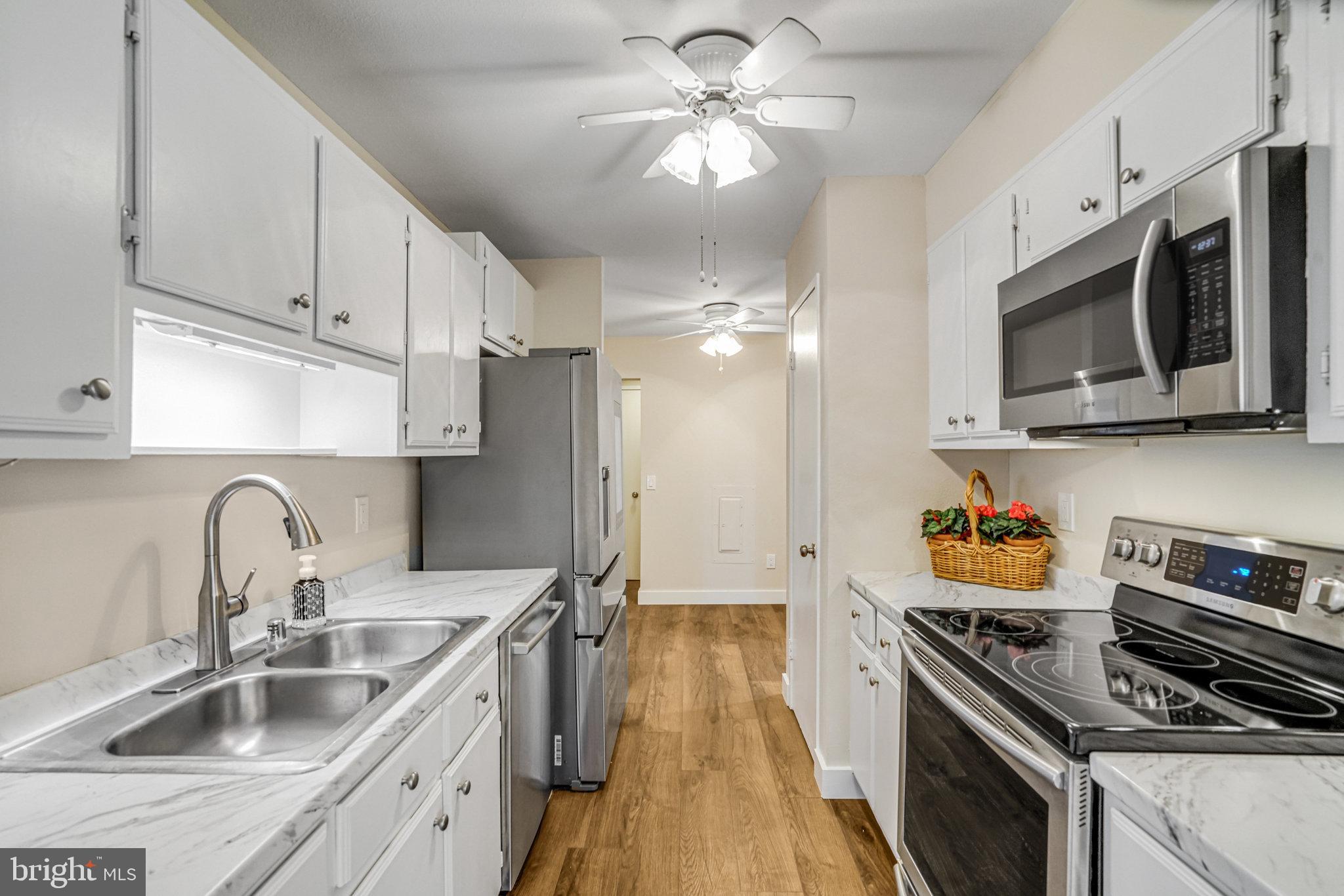 6101 Edsall Road, Unit 312 Alexandria, VA 22304 - Photo 15 of 57 a kitchen with stainless steel appliances a sink a stove oven a refrigerator with white cabinets and wooden floor