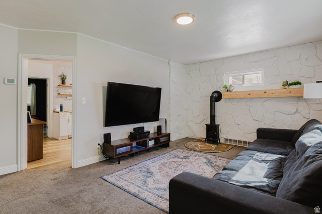 244 North 600 West Logan, UT 84321 - Photo 14 of 30 Living area featuring a stone accent wall, wood-finish flooring, and a freestanding stove