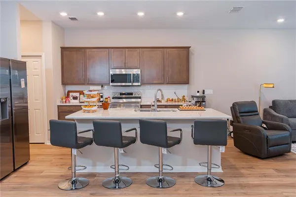 a kitchen with stainless steel appliances a sink a stove a refrigerator cabinets and wooden floor