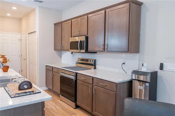 a kitchen with stainless steel appliances kitchen island granite countertop a refrigerator a stove a sink and a chairs