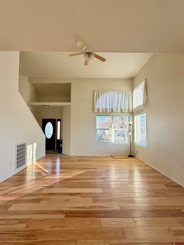 a view of an empty room with window and wooden floor
