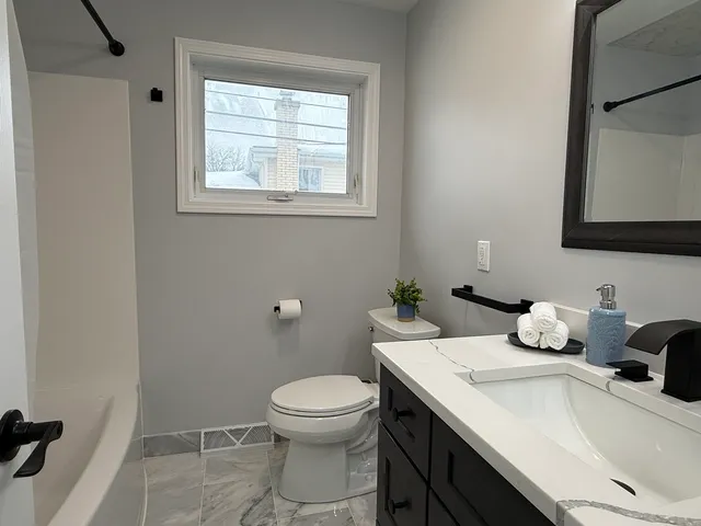 a bathroom with a granite countertop toilet sink and mirror