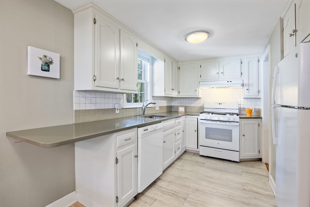 46 Spring Street Lexington, MA 02421 - Photo 11 of 32 a kitchen with granite countertop white cabinets and white appliances