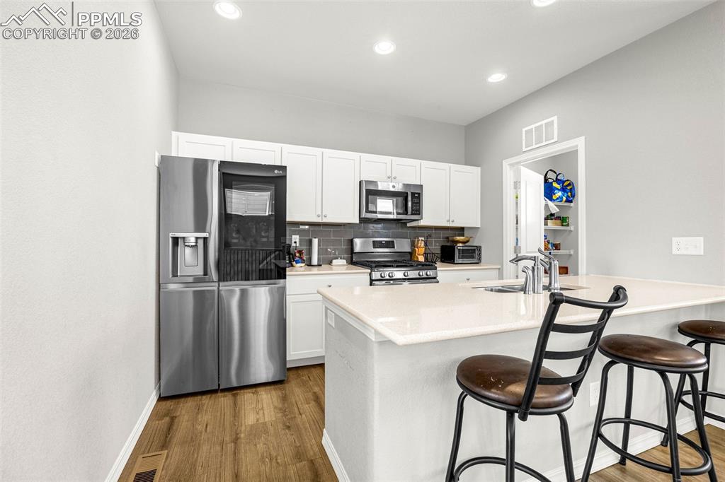 4432 Samaritan Loop Colorado Springs, CO 80916 - Photo 12 of 20 a kitchen with stainless steel appliances a stove top oven a refrigerator a sink a dining table and chairs with wooden floor