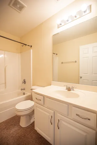 a view of a livingroom with a fireplace a ceiling fan and windows