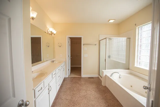 a spacious bathroom with a double vanity sink a large mirror and a shower