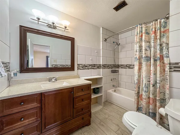 a bathroom with a double vanity sink a toilet a mirror and shower