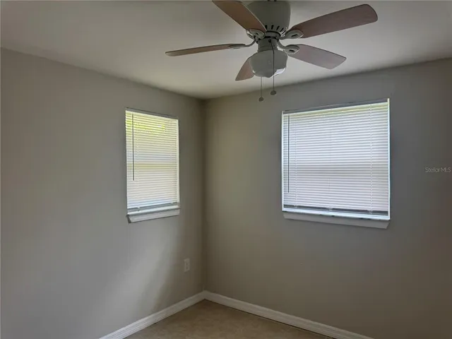 an empty room with a window and a fan