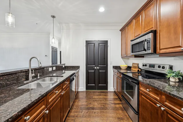 a kitchen with stainless steel appliances granite countertop a sink a stove and a wooden floor