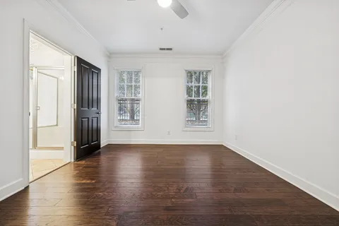 an empty room with wooden floor cabinet and windows