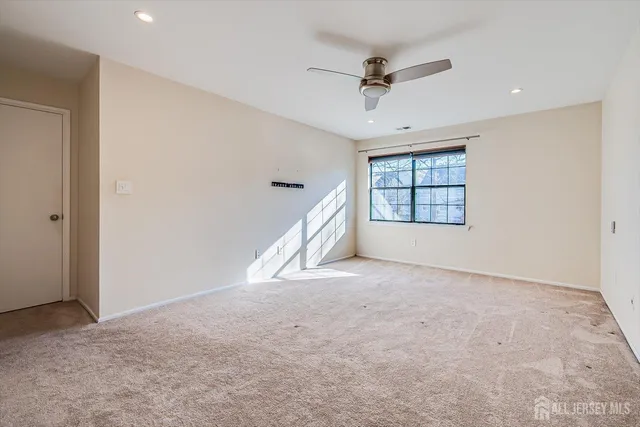 an empty room with windows and ceiling fan