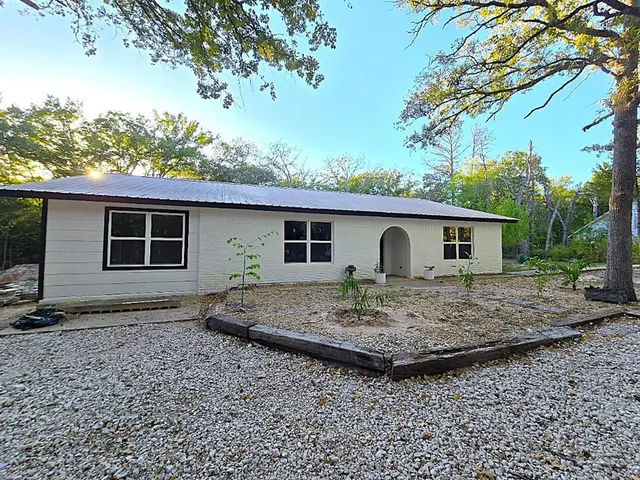 a view of a house with a small yard and large tree