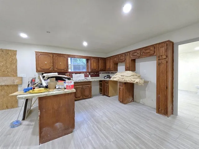 a kitchen with stainless steel appliances granite countertop a stove top oven a sink dishwasher and a refrigerator with wooden floor