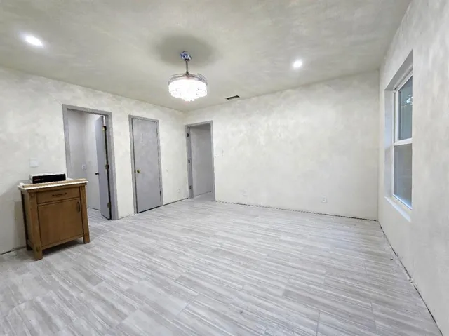 a view of an empty room with a window and wooden floor