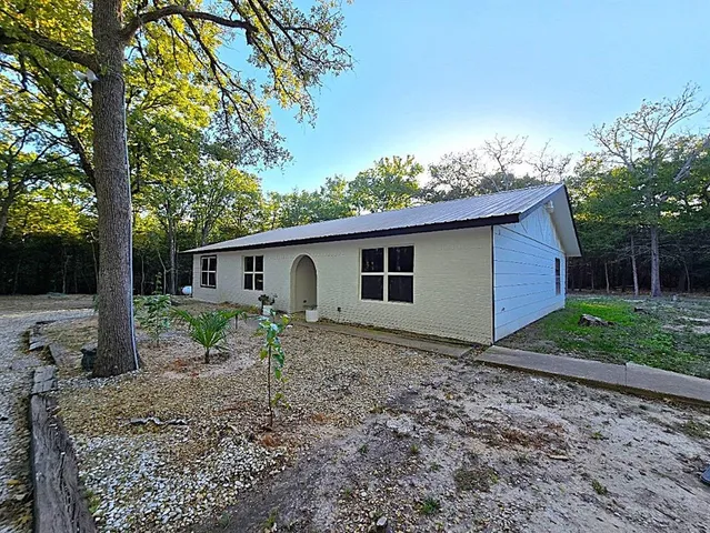 a view of a house with a yard and large tree